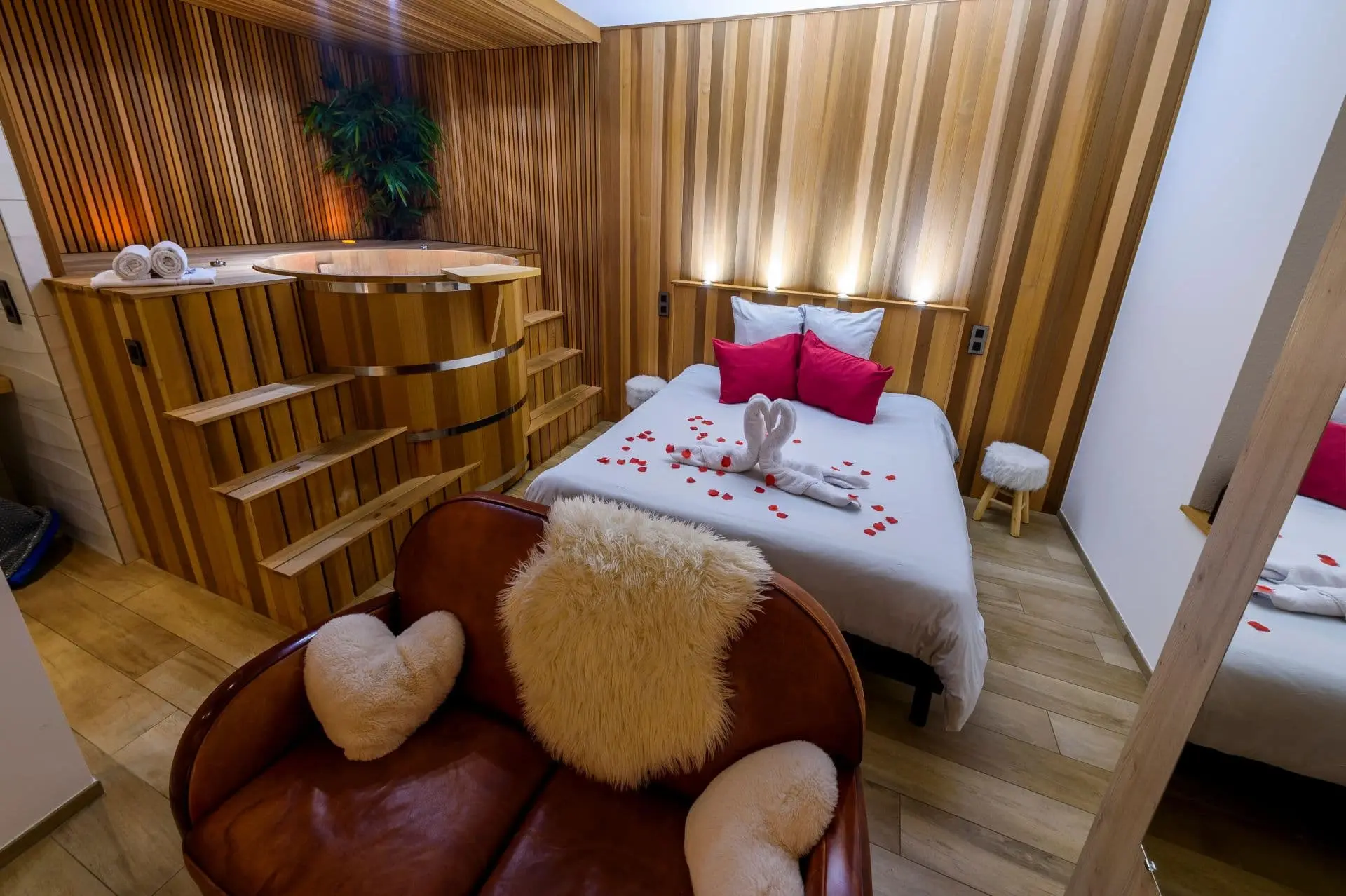 Intérieur chaleureux du Refuge d’Henry avec spa en bois et lit double